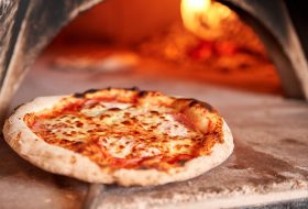 Baked tasty margherita pizza in Traditional wood oven in Naples restaurant, Italy. Original neapolitan pizza. Red hot coal